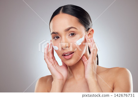 Apply lotion, portrait and woman in studio with skincare for dermatology, moisturizer and wellness routine on gray background. Face cream, Colombia female person and beauty or sunscreen and hands 142676731