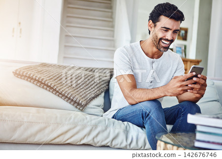 Man, phone and browsing with smile on sofa for networking, communication or social media in living room. Online, connection and person in lounge for notification, text message or internet app in home Man, phone and browsing with smile on sofa for networking, communication or social media in living room. Online, connection and person in lounge for notification, text message or internet app in home 142676746