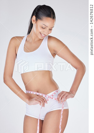 Woman, measuring tape and stomach in studio for progress, tracking weight loss and white background. Female person, check belly and results of liposuction on tummy, cosmetic change and transformation Woman, measuring tape and stomach in studio for progress, tracking weight loss and white background. Female person, check belly and results of liposuction on tummy, cosmetic change and transformation 142676812