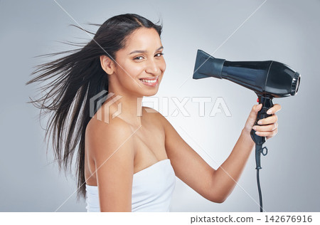 Hair, portrait and woman with hairdryer in studio for cosmetic, shine or heat protectant promo on grey background. Haircare, beauty or face of girl model with hot air tool for smooth, glow or results Hair, portrait and woman with hairdryer in studio for cosmetic, shine or heat protectant promo on grey background. Haircare, beauty or face of girl model with hot air tool for smooth, glow or results 142676916
