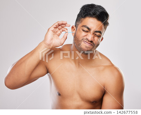 Man, hygiene or cleaning ear with bud in studio white background for model, freshness and cosmetics. Male person, topless and grooming with cotton for self care, wax removal and wellness or comfort Man, hygiene or cleaning ear with bud in studio white background for model, freshness and cosmetics. Male person, topless and grooming with cotton for self care, wax removal and wellness or comfort 142677558