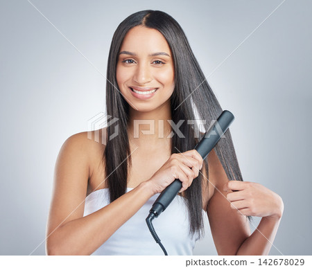 Portrait, beauty and happy woman with hair straightener in studio for style, treatment and shampoo shine results on grey background. Haircare, flat iron and model face with smooth, texture or growth 142678029