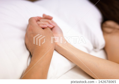 A man and a woman holding hands in bed A man and a woman holding hands in bed 142678065