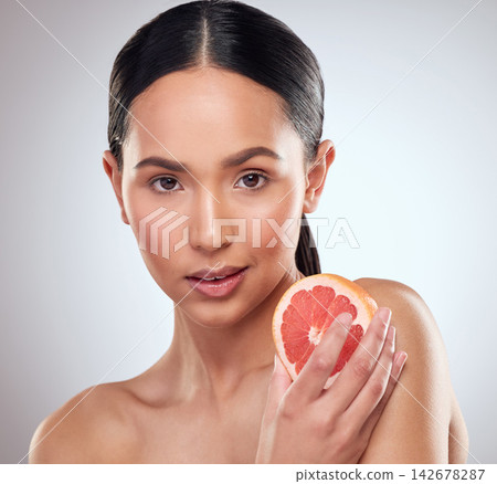 Beauty, diet and grapefruit with portrait of woman in studio on white background for wellness. Aesthetic, fruit and nutrition with face of serious model at spa for cosmetics, dermatology or skincare Beauty, diet and grapefruit with portrait of woman in studio on white background for wellness. Aesthetic, fruit and nutrition with face of serious model at spa for cosmetics, dermatology or skincare 142678287
