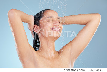 Girl, shower and water for cleaning in studio, skin care and hair for hygiene on blue background. Female person, cosmetic and liquid for bodycare or grooming, face and confident for washing routine Girl, shower and water for cleaning in studio, skin care and hair for hygiene on blue background. Female person, cosmetic and liquid for bodycare or grooming, face and confident for washing routine 142678330