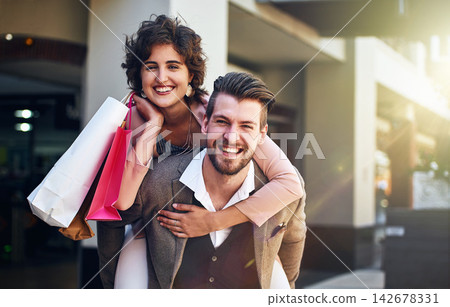 Shopping, piggy back and portrait of couple in city for clothing sale, discount deal and store promotion. Fashion, retail mall and happy man and woman for bonding, travel and tourism in urban town Shopping, piggy back and portrait of couple in city for clothing sale, discount deal and store promotion. Fashion, retail mall and happy man and woman for bonding, travel and tourism in urban town 142678331