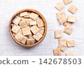 Cinnamon crunch squares, breakfast cereal in wooden bowl on linen. Flat pieces made from whole wheat and rice flour, with ridges, to look like mini slices of toast. Eaten with milk or as snack. Photo Cinnamon crunch squares, breakfast cereal in wooden bowl on linen. Flat pieces made from whole wheat and rice flour, with ridges, to look like mini slices of toast. Eaten with milk or as snack. Photo 142678503