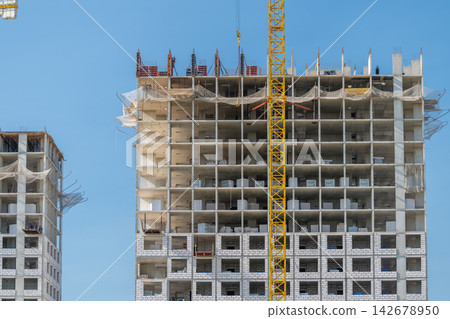 Construction progresses on a modern high-rise building surrounded by a clear blue sky Construction progresses on a modern high-rise building surrounded by a clear blue sky 142678950