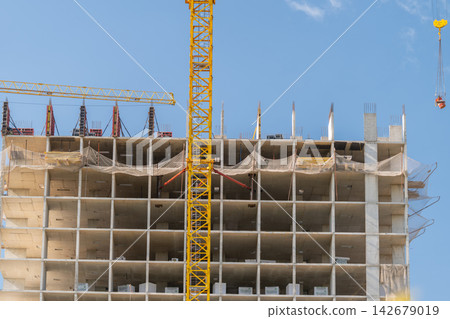 Construction progresses on a high-rise building under a clear blue sky in a bustling urban environment Construction progresses on a high-rise building under a clear blue sky in a bustling urban environment 142679019