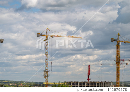 Construction cranes tower over a bustling urban site under a cloudy sky showcasing the vibrant energy of city development Construction cranes tower over a bustling urban site under a cloudy sky showcasing the vibrant energy of city development 142679278