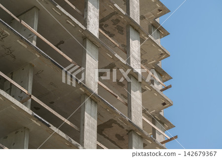 Concrete skeleton rises toward the clear blue sky as construction workers prepare for a new urban development project Concrete skeleton rises toward the clear blue sky as construction workers prepare for a new urban development project 142679367