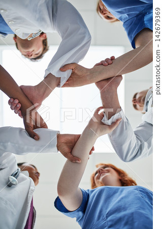 Doctor, hands together and below with medical team in unity, meeting or motivation at hospital. Low angle or closeup of people or group touching in collaboration, solidarity or mission at clinic Doctor, hands together and below with medical team in unity, meeting or motivation at hospital. Low angle or closeup of people or group touching in collaboration, solidarity or mission at clinic 142679369