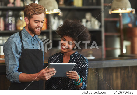 Barista, man and woman with tablet in coffee shop with discussion, choice or planning menu on app. People, reading and touchscreen for agreement in cafeteria with post on social network for promotion Barista, man and woman with tablet in coffee shop with discussion, choice or planning menu on app. People, reading and touchscreen for agreement in cafeteria with post on social network for promotion 142679453