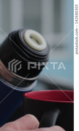 Vertical video. A woman pours herbal tea from a thermos, close-up. Vertical video. A woman pours herbal tea from a thermos, close-up. 142680305