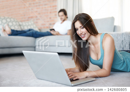 Happy, woman and floor with laptop at home in living room to relax by browse or streaming internet for entertainment. Smile, female person and digital technology in lounge for reading blog on website Happy, woman and floor with laptop at home in living room to relax by browse or streaming internet for entertainment. Smile, female person and digital technology in lounge for reading blog on website 142680805
