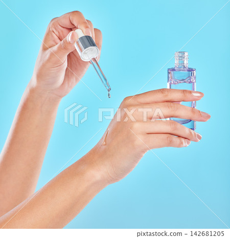 Hands, skincare and person with serum bottle in studio for glow or wellness on blue background. Product, closeup and model with hyaluronic acid, essential oil or cosmetics for aesthetics and beauty Hands, skincare and person with serum bottle in studio for glow or wellness on blue background. Product, closeup and model with hyaluronic acid, essential oil or cosmetics for aesthetics and beauty 142681205