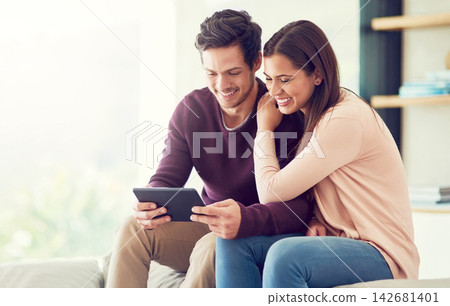 Happy, couple and relax with tablet in in living room for social media, news or streaming video together. Digital technology, man and woman on sofa for online shopping or reading blog on app in home Happy, couple and relax with tablet in in living room for social media, news or streaming video together. Digital technology, man and woman on sofa for online shopping or reading blog on app in home 142681401