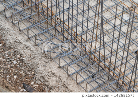 Construction excavation pit revealing a sturdy foundation framed by steel reinforcements in a bustling urban area during daylight 142681575