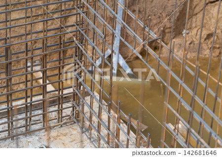 Construction site reveals the intricate patterns of steel rebar set against a backdrop of muddy water Construction site reveals the intricate patterns of steel rebar set against a backdrop of muddy water 142681646