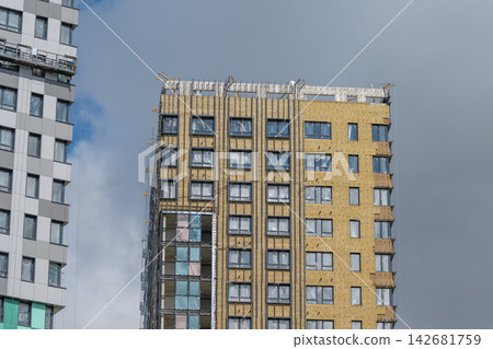 Urban development shapes the skyline as new buildings rise under a cloudy sky in a bustling city quarter Urban development shapes the skyline as new buildings rise under a cloudy sky in a bustling city quarter 142681759