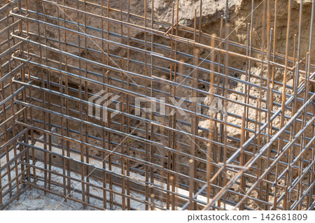 Steel framework rising from the earth in a construction site amidst the bright afternoon light Steel framework rising from the earth in a construction site amidst the bright afternoon light 142681809