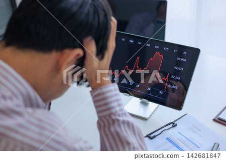 Stressed Investor Looking at Market Crash Stock Chart on Tablet in Office. Stressed Investor Looking at Market Crash Stock Chart on Tablet in Office. 142681847