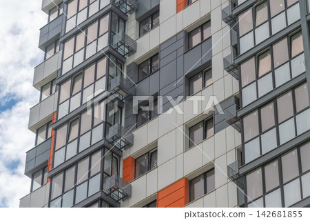 Modern architecture showcases striking design elements on a high-rise building under a vivid sky Modern architecture showcases striking design elements on a high-rise building under a vivid sky 142681855