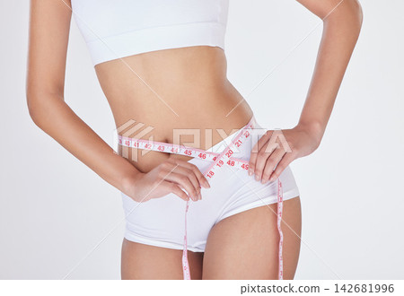 Woman, measuring tape and stomach in studio for weight loss, tracking progress and white background. Female person, slimming and results of liposuction or tummy tuck, cosmetic change and underwear Woman, measuring tape and stomach in studio for weight loss, tracking progress and white background. Female person, slimming and results of liposuction or tummy tuck, cosmetic change and underwear 142681996