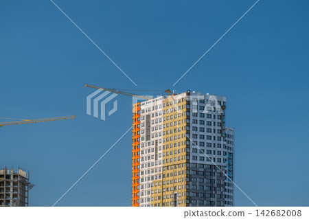 New building emerges against a clear sky cranes busy at work during midday construction in the heart of the city New building emerges against a clear sky cranes busy at work during midday construction in the heart of the city 142682008