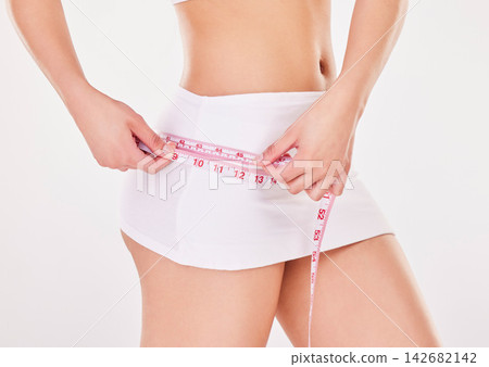 Woman, hand and waist with measuring tape in studio for weight loss, results or progress of diet. Female person, underwear and healthy with body for self care, wellness or check on white background Woman, hand and waist with measuring tape in studio for weight loss, results or progress of diet. Female person, underwear and healthy with body for self care, wellness or check on white background 142682142