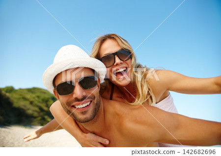 Couple, sunglasses and piggyback on vacation, smile and peace at beach or game by blue sky. People, happy and tropical island for bonding on weekend, outdoor nature and love for marriage or romance Couple, sunglasses and piggyback on vacation, smile and peace at beach or game by blue sky. People, happy and tropical island for bonding on weekend, outdoor nature and love for marriage or romance 142682696