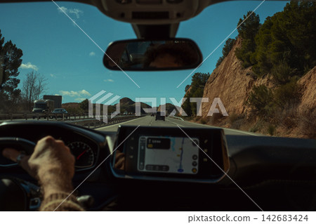 Person driving a car on an open road, navigating using the dashboard gps screen, enjoying a journey amidst rural scenery Person driving a car on an open road, navigating using the dashboard gps screen, enjoying a journey amidst rural scenery 142683424