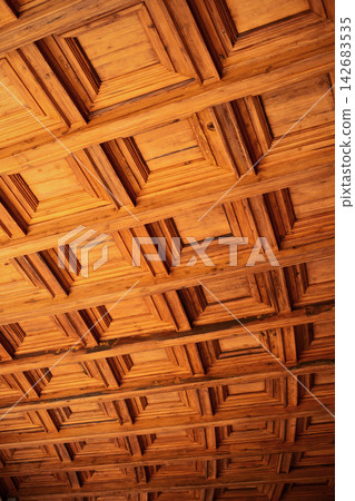 Wooden coffered ceiling showing geometric square panels, creating a textured pattern and enhancing architectural details Wooden coffered ceiling showing geometric square panels, creating a textured pattern and enhancing architectural details 142683535