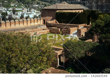 Ancient alhambra fortress gardens with terraced stone walls and historic buildings, offering views of granada city Ancient alhambra fortress gardens with terraced stone walls and historic buildings, offering views of granada city 142683544
