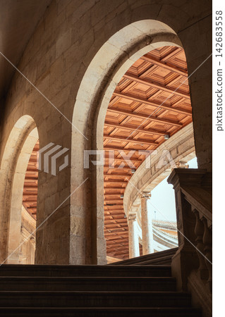 Arched stone hallway leading to a grand wooden ceiling and spiral staircase in an ancient palace Arched stone hallway leading to a grand wooden ceiling and spiral staircase in an ancient palace 142683558