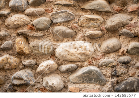 Ancient stone wall showing weathered masonry texture with natural river stones and rough mortar patterns Ancient stone wall showing weathered masonry texture with natural river stones and rough mortar patterns 142683577