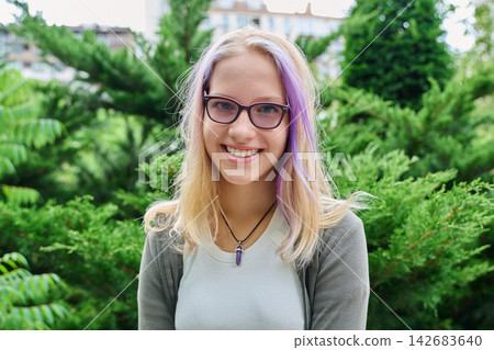 Smiling teenage girl wearing glasses looking at camera outdoors portrait 142683640