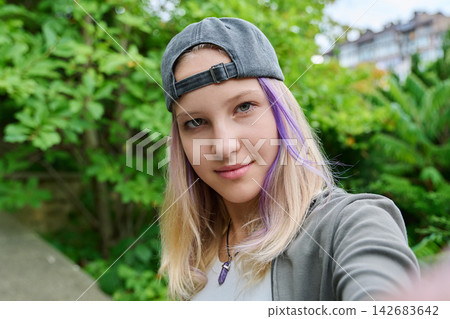 Teenage girl taking selfie outdoors looking at camera close up portrait 142683642
