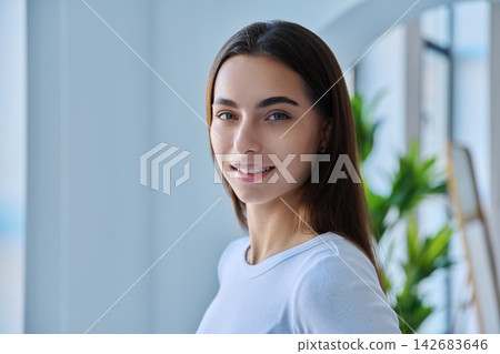 Smiling young female student headshot in modern indoor setting Smiling young female student headshot in modern indoor setting 142683646
