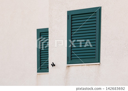 Green shutters on a white stucco wall with minimal architectural detail Green shutters on a white stucco wall with minimal architectural detail 142683692