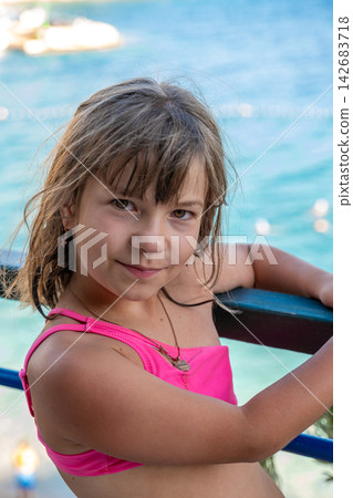 Smiling young girl posing by turquoise water on sunny vacation Smiling young girl posing by turquoise water on sunny vacation 142683718