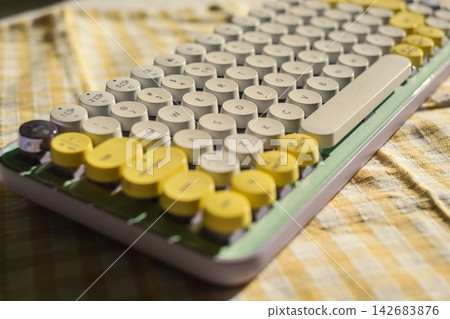 Retro keyboard on checkered fabric with yellow accents under sunlight Retro keyboard on checkered fabric with yellow accents under sunlight 142683876