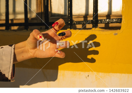 Creative hand gesture with unique colorful nail art in warm lighting Creative hand gesture with unique colorful nail art in warm lighting 142683922