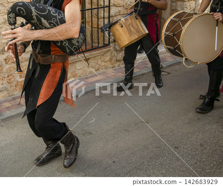 Performers in period costumes play bagpipes and drums during outdoor procession Performers in period costumes play bagpipes and drums during outdoor procession 142683929