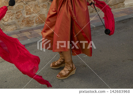 Dancer with red silk poi ribbons and terracotta dress performing outdoors 142683968