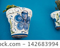 Vibrant ceramic flower pot with colorful floral design against blue wall 142683994