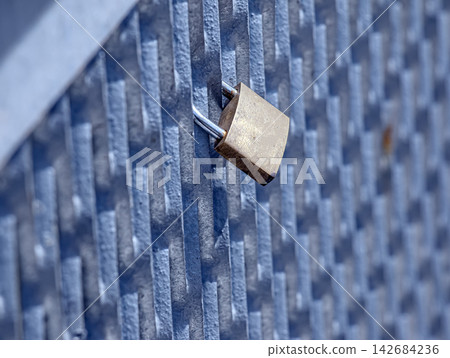 Weathered Brass Padlock on Blue Metal Fence Weathered Brass Padlock on Blue Metal Fence 142684236