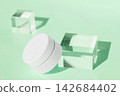 Cosmetic container with cream among glass cubes on green background 142684402