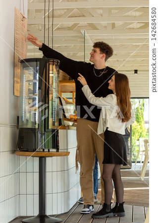Young couple choosing food from a wall menu Young couple choosing food from a wall menu 142684580