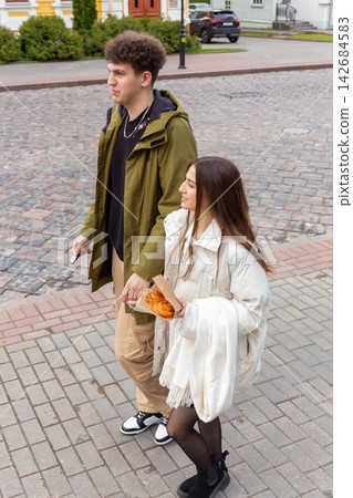 Young couple walking hand in hand on cobblestone street Young couple walking hand in hand on cobblestone street 142684583
